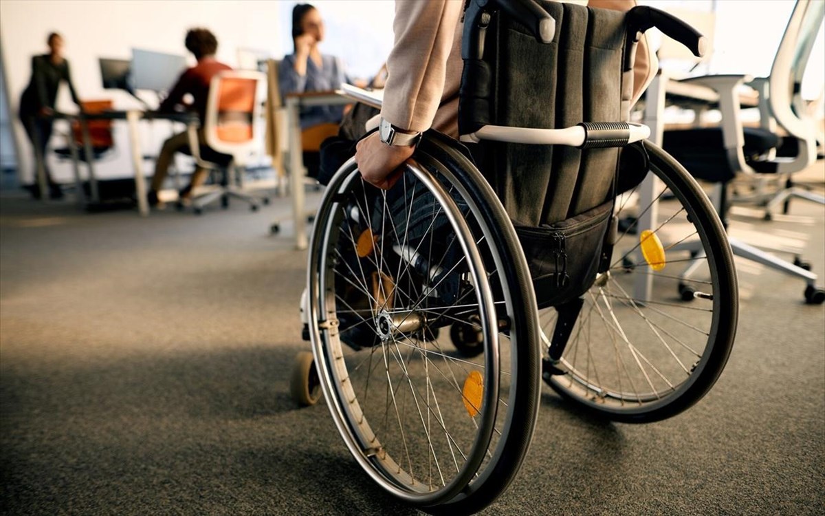 rearviewofbusinesswomanwithdisabilityuseswheelchairwhilegoing