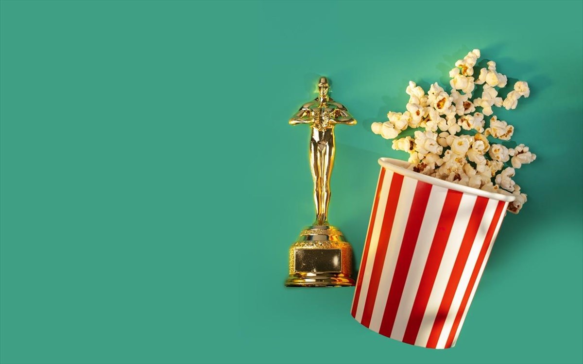 oscartrophywithpopcornbucketongreenbackgroundstripedsnack