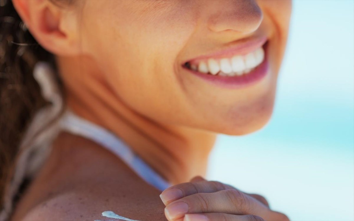 closeuponhappyyoungwomanapplyingsunblockcreme
